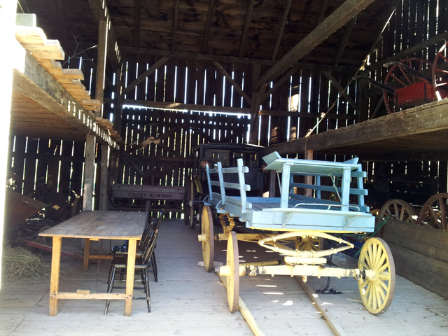 wagon and carriage and tableand chairs inside a barn