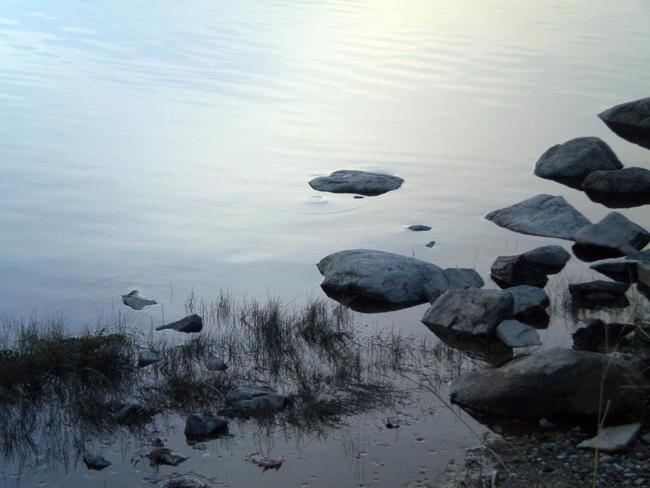 Stones along the shoreline of the Saint John River at sunset.